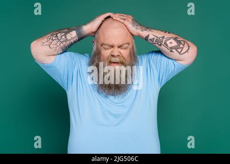 l'uomo arrabbiato con il peso eccessivo che tocca la testa del calvo isolato sul verde Foto Stock