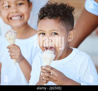 Dolce per i bambini. Shot di un adorabile ragazzo e ragazza che mangiano un cono gelato mentre si siede all'esterno. Foto Stock