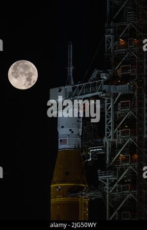 Una luna piena sorge sul razzo della NASA Artemis i Space Launch System con la navicella spaziale Orion a bordo di un lanciatore mobile al Launch Complex 39B, presso il Kennedy Space Center, 14 giugno 2022, a Cape Canaveral, Florida. SLS e Orion sono in fase di preparazione per una prova di vestito umido per mettere in pratica le tempistiche e le procedure di lancio. Foto Stock