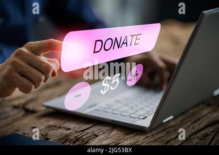 Dona denaro online. Pagamento della donazione su laptop Foto Stock