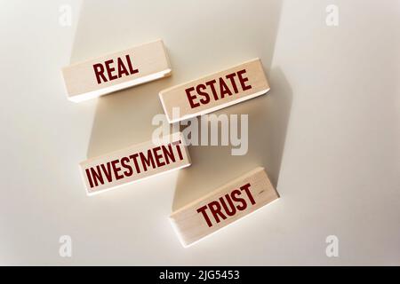 REIT fondo d'investimento simbolo. Parole concettuali REIT fondo di investimento immobiliare su blocchi di legno su sfondo bianco. Investimento immobiliare fiducia RE Foto Stock