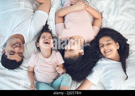 Ci completano. Scatto di una bella famiglia giovane che parla e si lega a letto insieme. Foto Stock