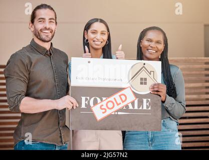 Proprietari di abitazione riusciti. Shot di una giovane coppia e il loro agente immobiliare tenendo un bordo venduto fuori della loro casa. Foto Stock