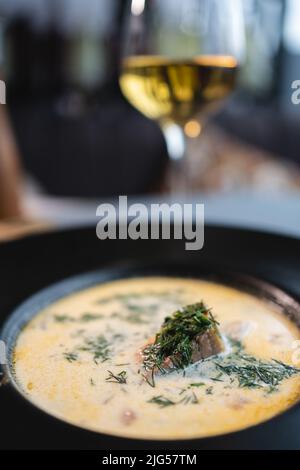 primo piano di zuppa di panna con pesce di salmone, patate e aneto verde in ciotola sul tavolo Foto Stock