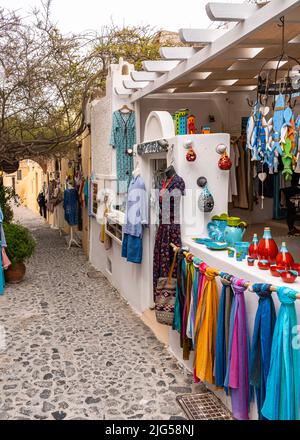 Oia, Santorini, Grece, 2022 aprile – vicolo panoramico con un negozio che vende abiti colorati e prodotti artigianali Foto Stock