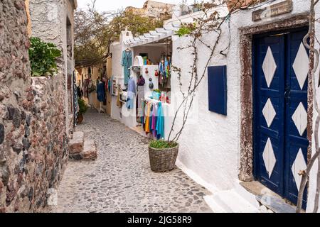 Oia, Santorini, Grece, 2022 aprile – vicolo panoramico con un negozio che vende abiti colorati e prodotti artigianali Foto Stock