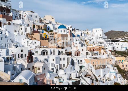 Vista panoramica della città di Oia a Santorini con case dipinte di bianco e una piccola chiesa con cupole blu, Grecia Foto Stock