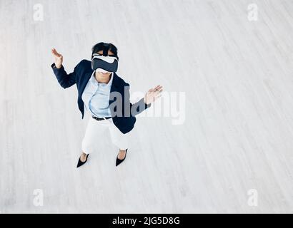 Eccitato da tutte le possibilità che vede. Scatto ad alta angolazione di una giovane donna d'affari che indossa un visore VR in ufficio. Foto Stock