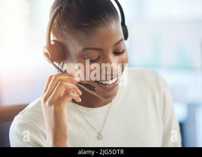 Che cosa possiamo fare per voi oggi? Scatto corto di una giovane e attraente agente del call center femminile che lavora nel suo ufficio. Foto Stock