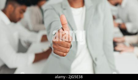 Darti un pollice in su. Colpo di un businessperson irriconoscibile che mostra un pollice in su sul lavoro. Foto Stock