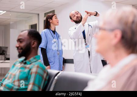 Personale medico diversificato che parla di assistenza sanitaria in ricezione ospedale, discutere di pazienti e appuntamenti presso la hall delle strutture mediche. Medico e infermiere nella sala d'attesa. Foto Stock