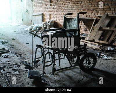 Vecchia sedia a rotelle derelitto all'interno dell'ospedale abbandonato in rovina Foto Stock