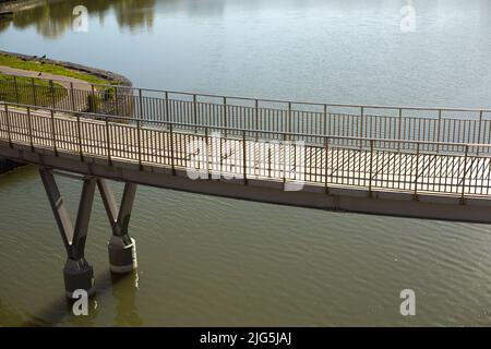 Ponte pedonale sull'acqua. Ponte con ringhiere. Dettagli del parco in città. Argine sul lago. Foto Stock