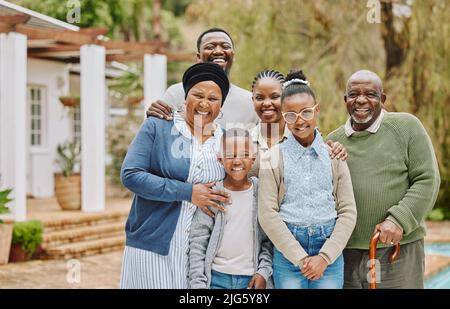 Le visite in famiglia sono le migliori. Ritratto ritagliato di una famiglia multigenerazionale che si trova all'esterno del giardino. Foto Stock