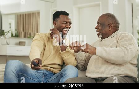 Una famiglia felice è solo un cielo più vecchio. Scatto di un padre e di un figlio che ridono nel salotto. Foto Stock