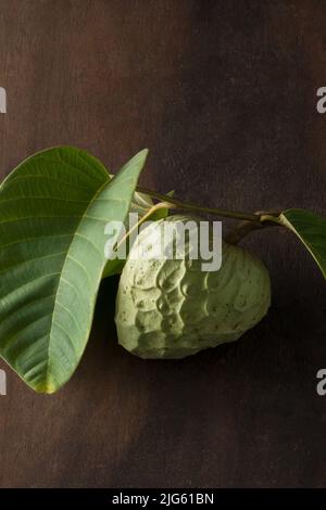 cherimoya, annona cherimoya, frutta commestibile a forma di cono conosciuta anche come mela crema o mela zucchero, frutta tropicale dal gusto dolce con foglie Foto Stock