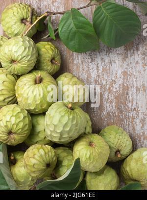 cherimoya, annona cherimoya, frutta commestibile a forma di cono conosciuta anche come mela crema o mela zucchero, mucchio di frutta tropicale dal gusto dolce con foglie Foto Stock