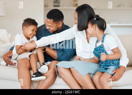 Una famiglia si prende cura dei propri. Scatto di una giovane famiglia che si unisce felicemente sul divano a casa. Foto Stock