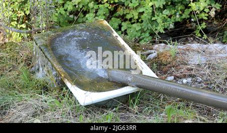 vecchia vasca da bagno utilizzata come un abbeveratoio per le mucche e un tubo che li fornisce di acqua fresca nella fattoria Foto Stock