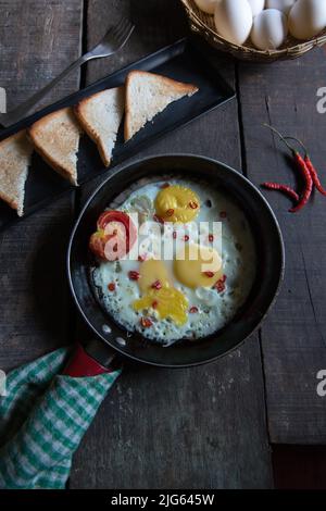 La prima colazione è composta da uova fritte in una pentola da cucina. Vista dall'alto, messa a fuoco selettiva. Foto Stock