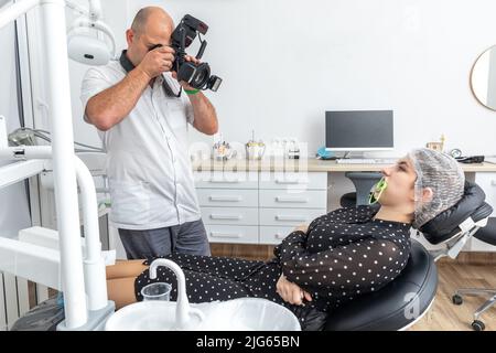 Dentista fotografando i denti del paziente per cartella medica prima e dopo l'intervento chirurgico in studio dentista Foto Stock
