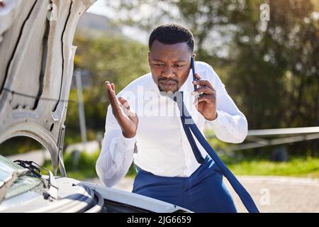Im sta per essere in ritardo per la mia riunione. Scatto corto di un bel uomo d'affari al telefono con assistenza stradale dopo aver subito un guasto del veicolo. Foto Stock