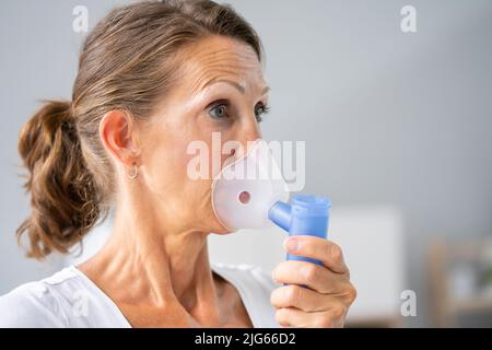 Donna con asma usando un inalatore per asmatici per prevenire attacchi Foto Stock
