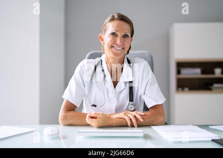 Ritratto di una donna felice medico con stetoscopio sulla scrivania Foto Stock