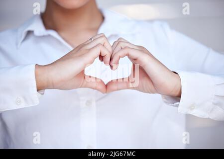 Metti il tuo cuore in tutto ciò che fai. Scatto corto di una donna d'affari irriconoscibile che forma una figura del cuore con le sue mani. Foto Stock