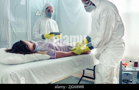 Medici che prendono il campione di sangue dal paziente che giace su un gurney Foto Stock