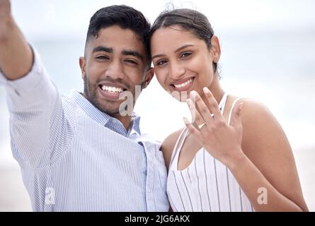 Si sposavano. Ritratto corto di una giovane coppia appena tradita che mostra il loro impegno sulla spiaggia. Foto Stock