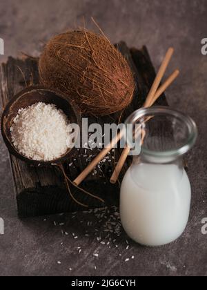 Bottiglia di latte vegano di cocco con paillette, cocco intero e fiocchi Foto Stock