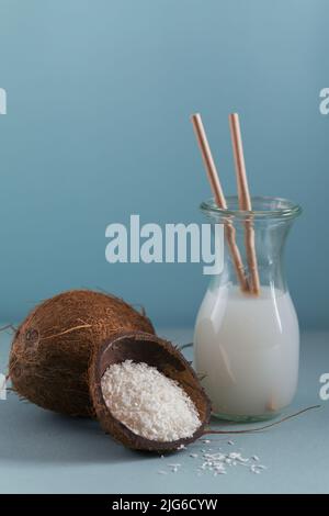 Bottiglia di latte vegano di cocco con paillette, cocco intero e fiocchi Foto Stock