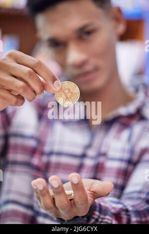 Unisciti alla mia rete peer-to-peer. Colpo di un giovane che detiene bitcoins. Foto Stock