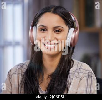 Contenuto nel mio appartamento. Scatto di un giovane studente con le cuffie mentre studia a casa. Foto Stock