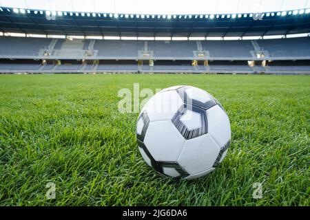 Football ball on fresh green grass pitch. Soccer ball at big stadium Foto Stock