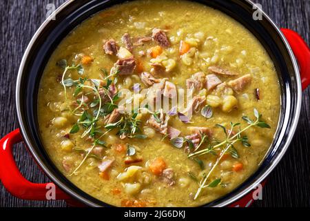 Primo piano della zuppa finlandese di piselli spezzati Hernekeitto con prosciutto in pentola rossa Foto Stock