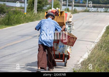 SAMUT PRAKAN, THAILANDIA, GIUGNO 01 2022, un vecchio uomo che spinge un carrello con un carico di materiale riciclabile Foto Stock