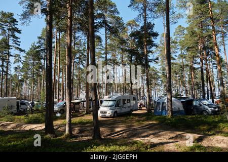 Regione di Leningrad, Russia - Giugno 2022. Festival di case mobili in foresta di conifere. Ci sono molte auto diverse per viaggiare, rimorchi e minivan Foto Stock