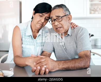 Possiamo superare tutti i cattivi insieme. Scatto di una coppia anziana che guarda infelice a casa. Foto Stock