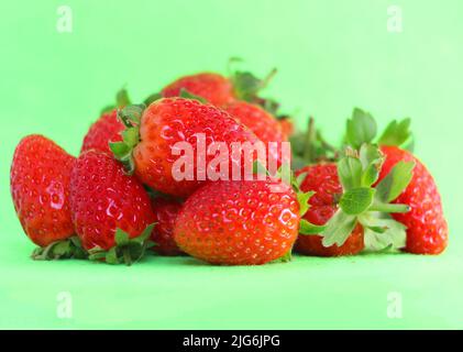 Frutta di fragola piccola dolce sulla carta da parati di fondo verde foglio Foto Stock