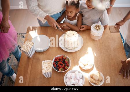 Natures modo di dire a noi di mangiare più torta. Shot di una famiglia che si prepara a mangiare una torta in una festa di compleanno a casa. Foto Stock