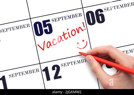 5th settembre. Una mano che scrive un testo DI VACANZA e che disegna un volto sorridente su una data di calendario 5 settembre . Concetto di pianificazione delle vacanze. Autunno mon Foto Stock