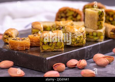 Varietà di pistacchio baklava. Varietà di baklava su sfondo scuro. Prelibatezze della cucina tradizionale turca. Dessert con sciroppo di pistacchio in Th Foto Stock