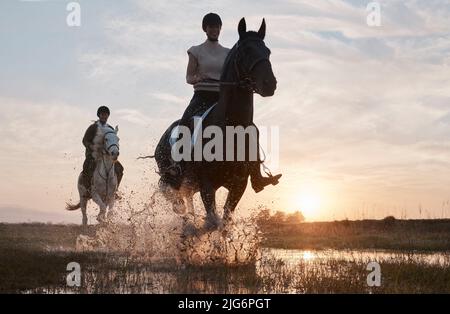 Il tramonto è il nostro momento preferito della giornata. Shot di due giovani donne a cavallo insieme. Foto Stock