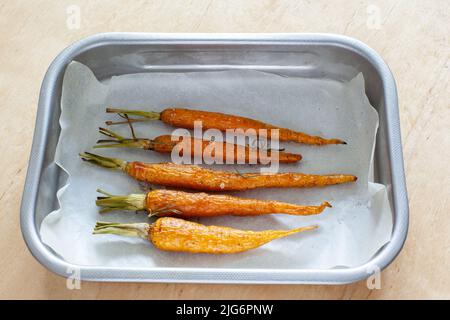 Carota intera giovane arrosto con verdure e sale marino in teglia da forno Foto Stock