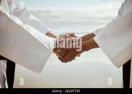 Il codice dei combattenti. Primo piano di due artisti marziali irriconoscibili che praticano il karate sulla spiaggia. Foto Stock