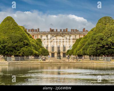 Fronte est dell'Hampton Court Palace incorniciato dai grandi alberi della fontana con l'acqua lunga in primo piano. Londra. REGNO UNITO. Foto Stock