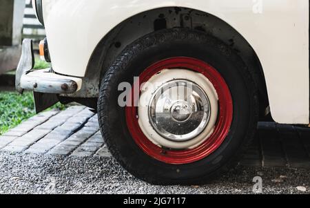 Foto ravvicinata della ruota bianca rossa di un'auto parcheggiata su una strada Foto Stock