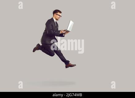 Un giovane uomo d'affari di successo che corre con un notebook in fretta per aumentare la sua carriera. Foto Stock